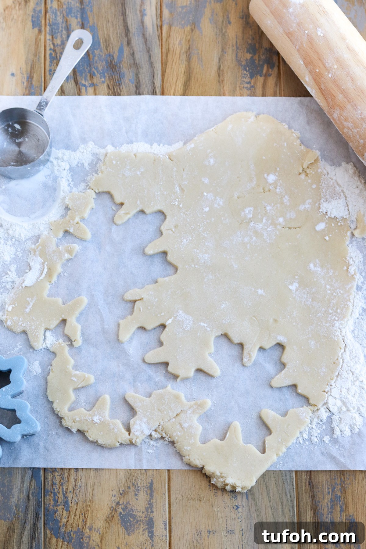 Soft Cut-Out Sugar Cookies Recipe for Tender, Perfect Shapes 7 Sugar cookie dough rolled out on board, cutting into shapes using metal cookie cutters.