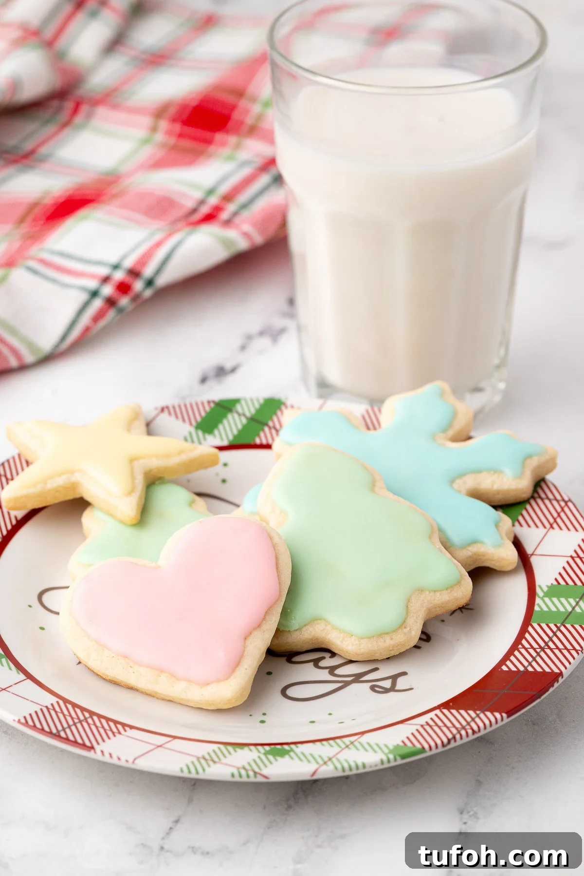 Soft Cut-Out Sugar Cookies Recipe for Tender, Perfect Shapes 9 A plate of frosted Christmas cookies waiting for Santa, with a glass of milk.
