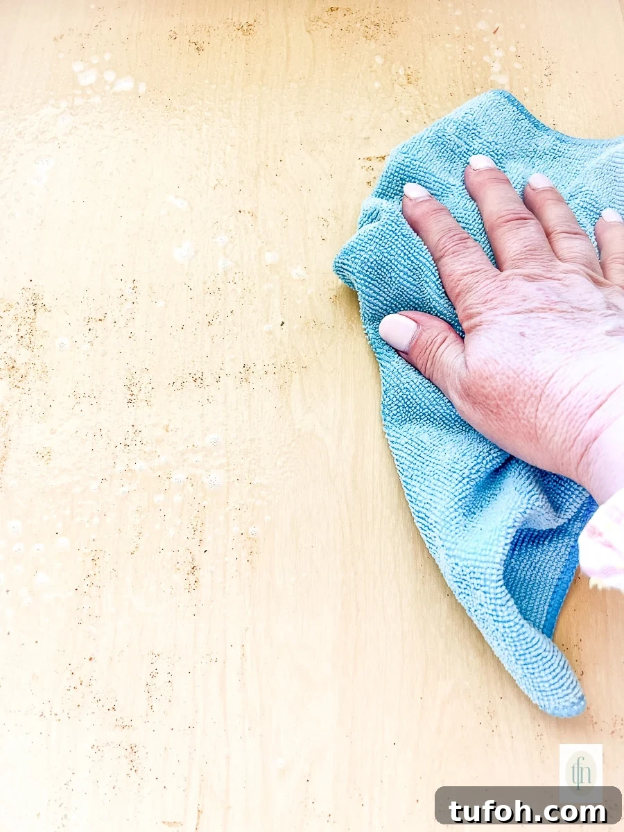 Using a microfiber cloth and food safe cleaner to wipe out the inside of a dirty spice drawer.