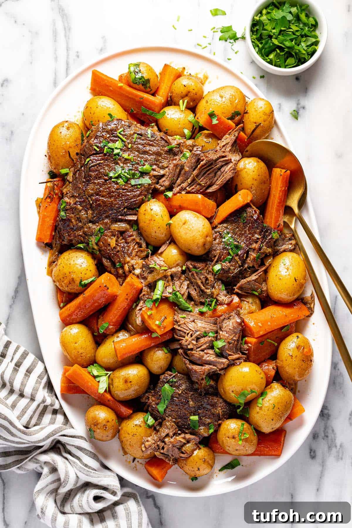 Slow-Cooker Pot Roast with Rich Homemade Gravy 2 Large serving platter filled with shredded pot roast, carrots, and potatoes garnished with parsley.