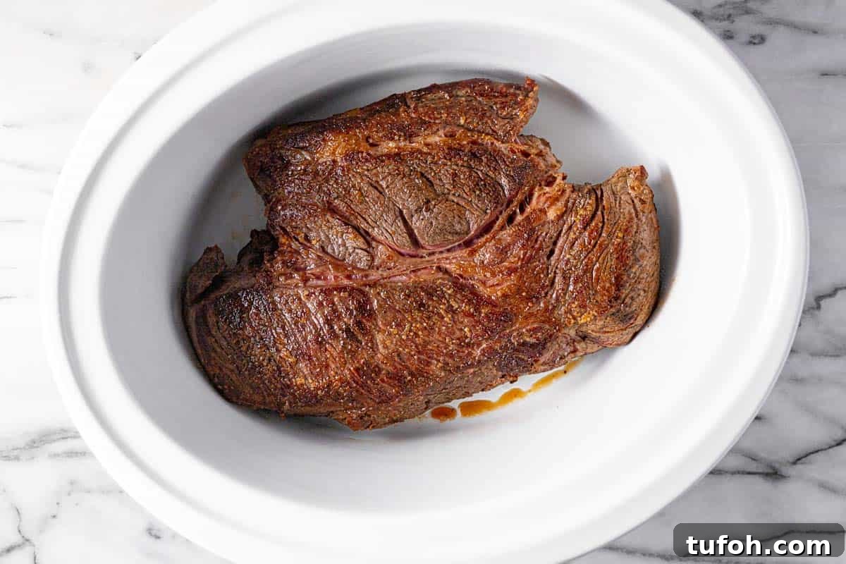 Slow-Cooker Pot Roast with Rich Homemade Gravy 4 Large crock pot insert with a seared pot roast in it.