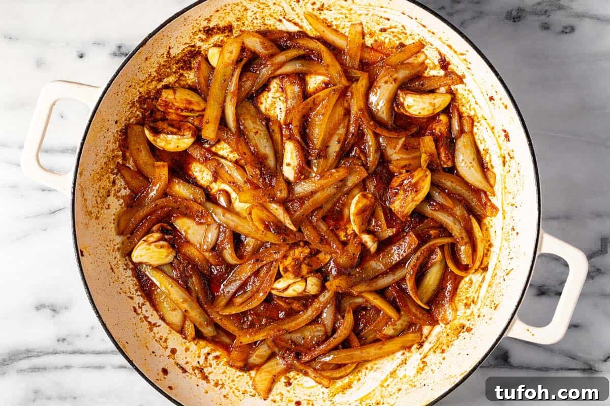 Slow-Cooker Pot Roast with Rich Homemade Gravy 5 Large white pan filled with sliced onion, garlic, and tomato paste.