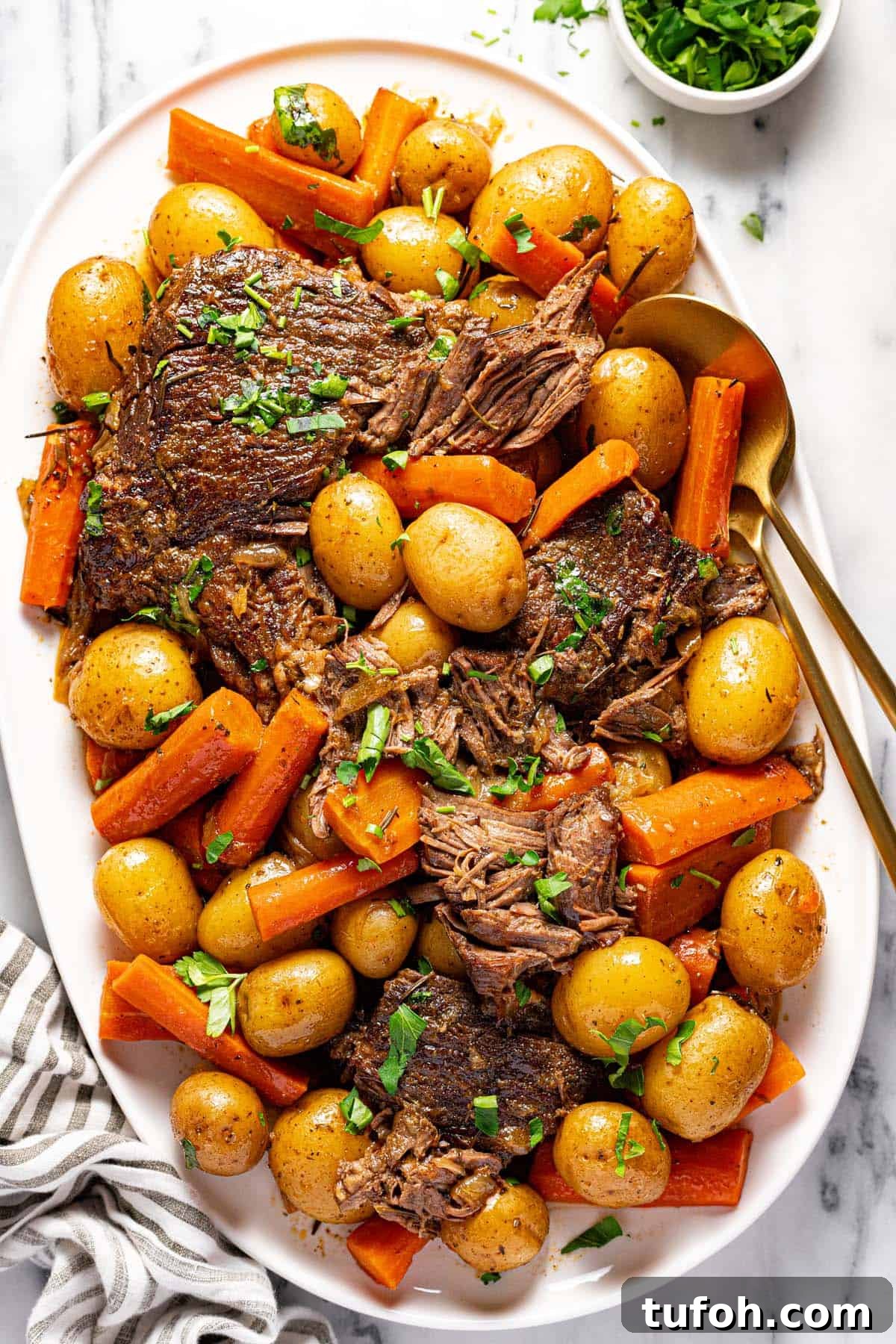 Slow-Cooker Pot Roast with Rich Homemade Gravy 8 Large serving platter filled with shredded pot roast, carrots, and potatoes garnished with parsley.