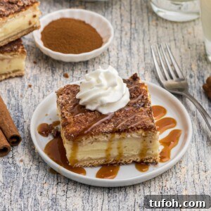 Churro Cheesecake Recipe: Cinnamon-Sugar Cheesecake Bars 13 Slice of churro cheesecake served on a small white plate in front of glasses of milk, with a drizzle of caramel sauce and whipped cream on top.