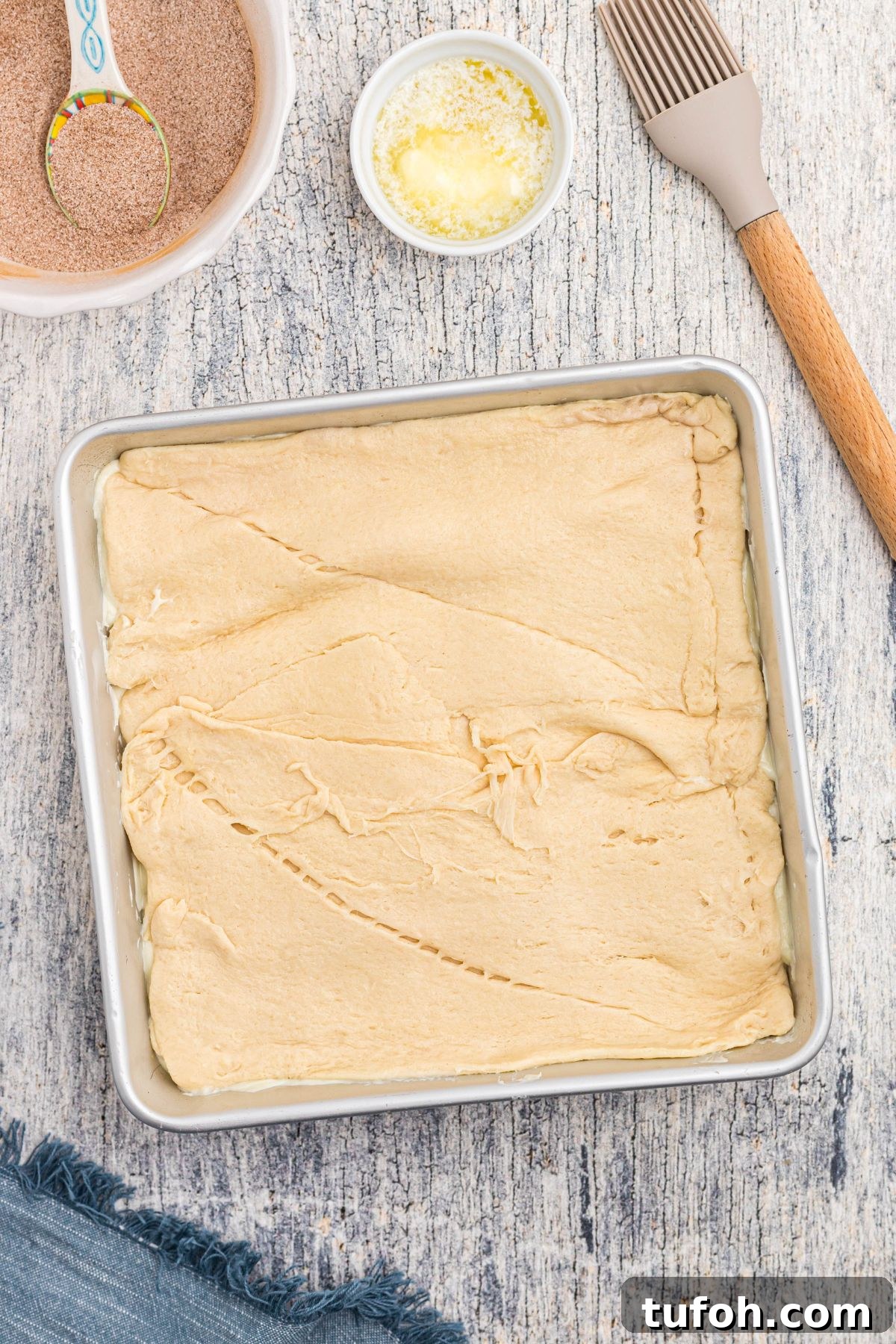 Churro Cheesecake Recipe: Cinnamon-Sugar Cheesecake Bars 8 Crescent roll dough rolled out and topping cheesecake filling.