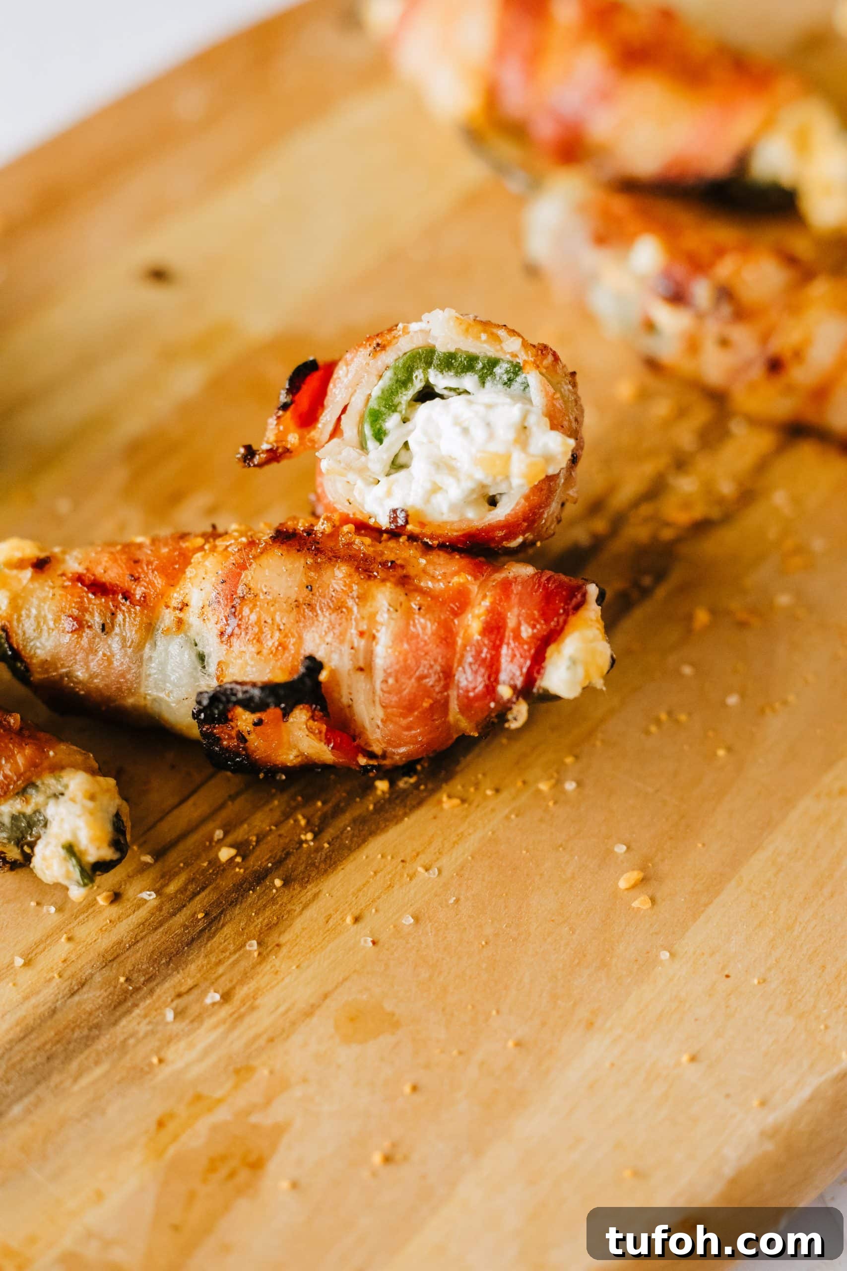 halved grilled jalapeno poppers on a wooden cutting board