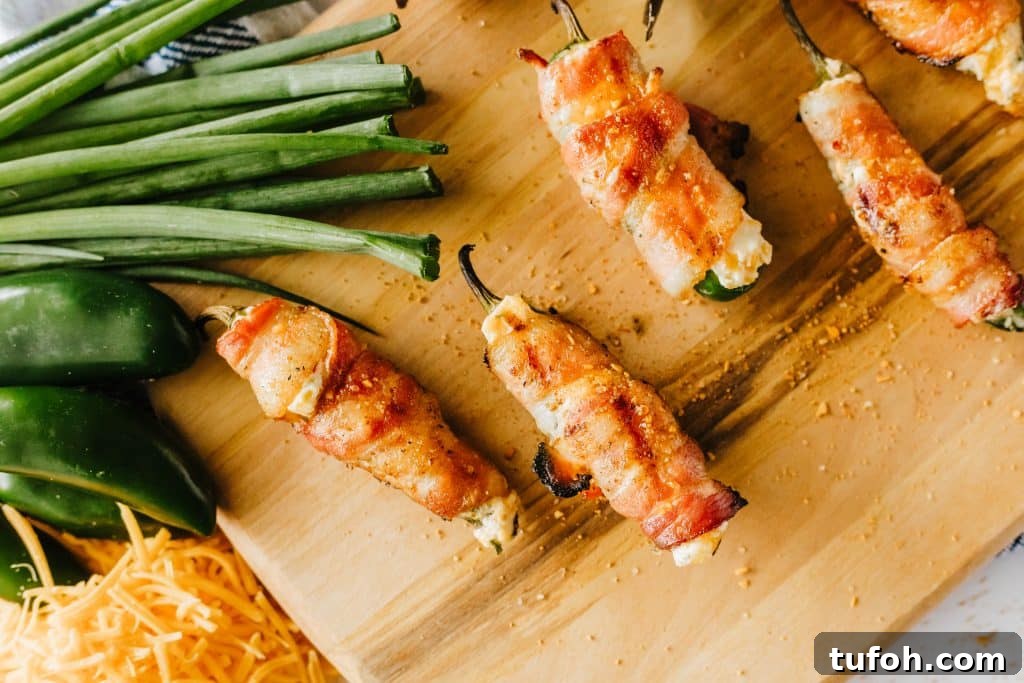 bacon wrapped grilled jalapeno poppers on a wooden cutting board