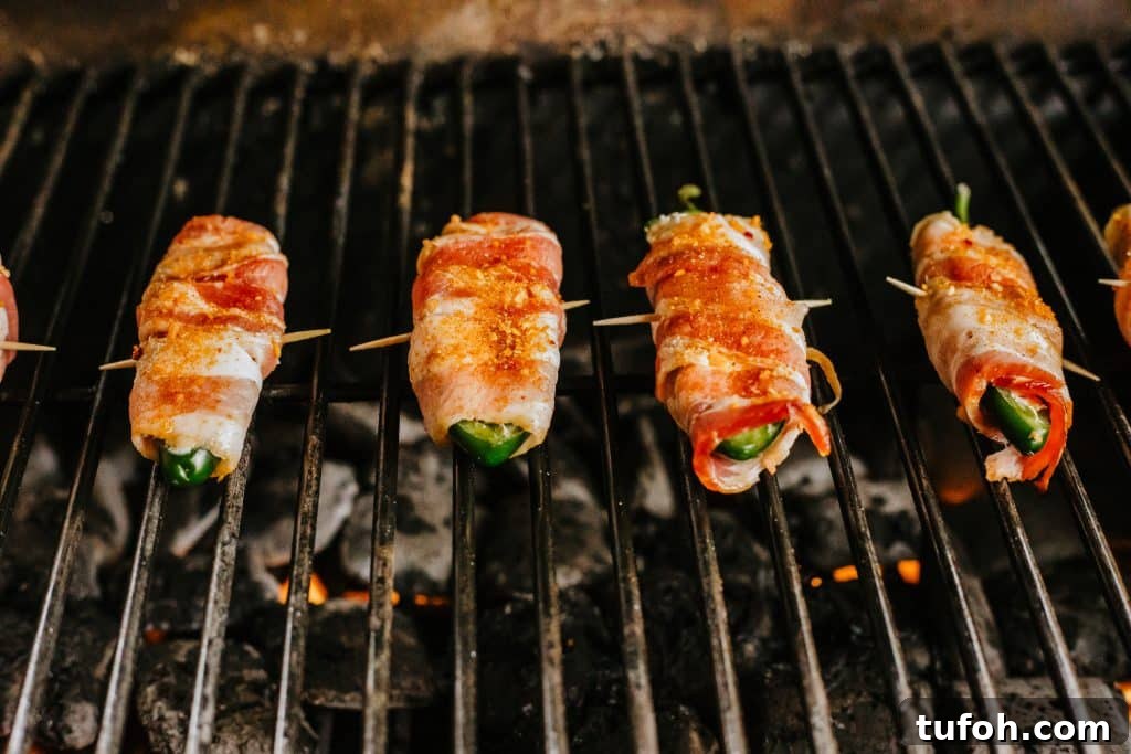 bacon wrapped jalapeno poppers on a hot grill wrack
