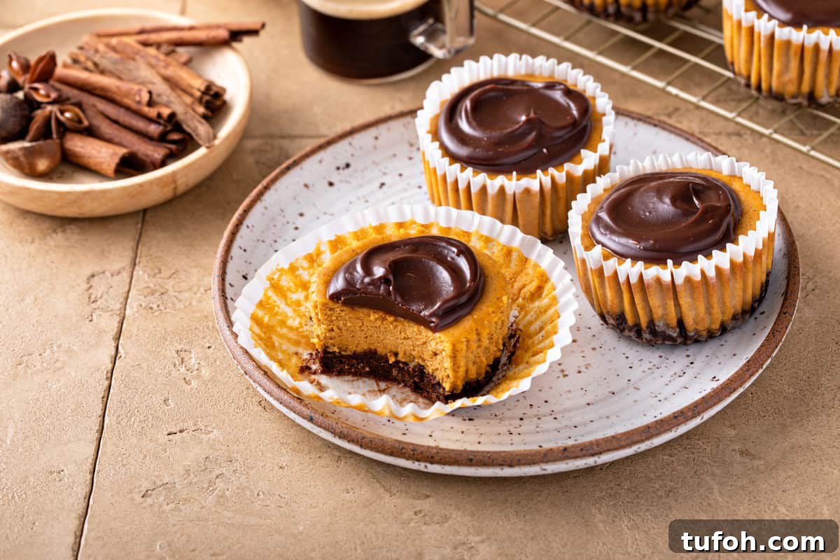 Three mini pumpkin cheesecakes on a plate. One of them is unwrapped and has a bite taken out of it.