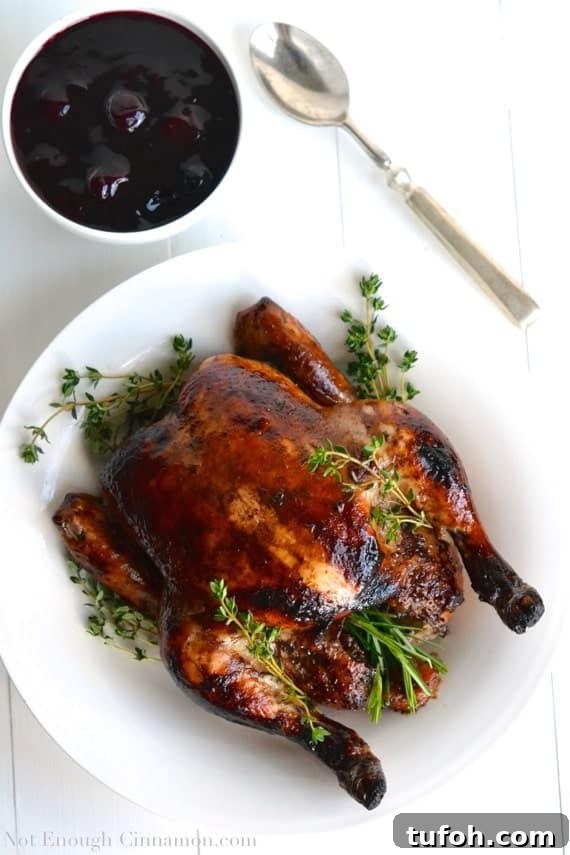 Balsamic Roasted Chicken with Cherry Pan Sauce 4 Balsamic marinated Roasted Chicken with perfect crispy skin served on a white platter with a side dish of homemade Easy Cherry Sauce in the background