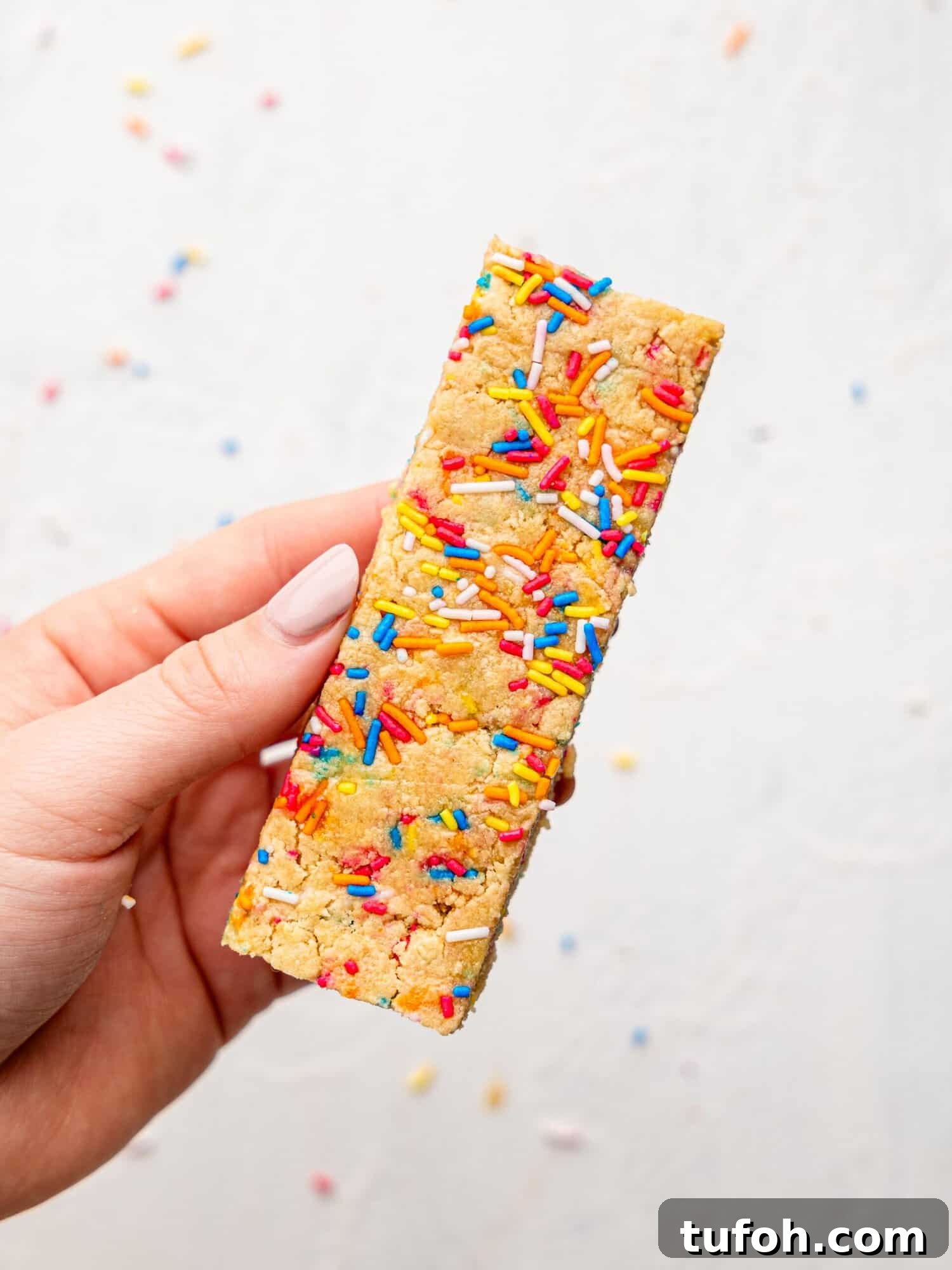 Hand holding a birthday cake protein bar.