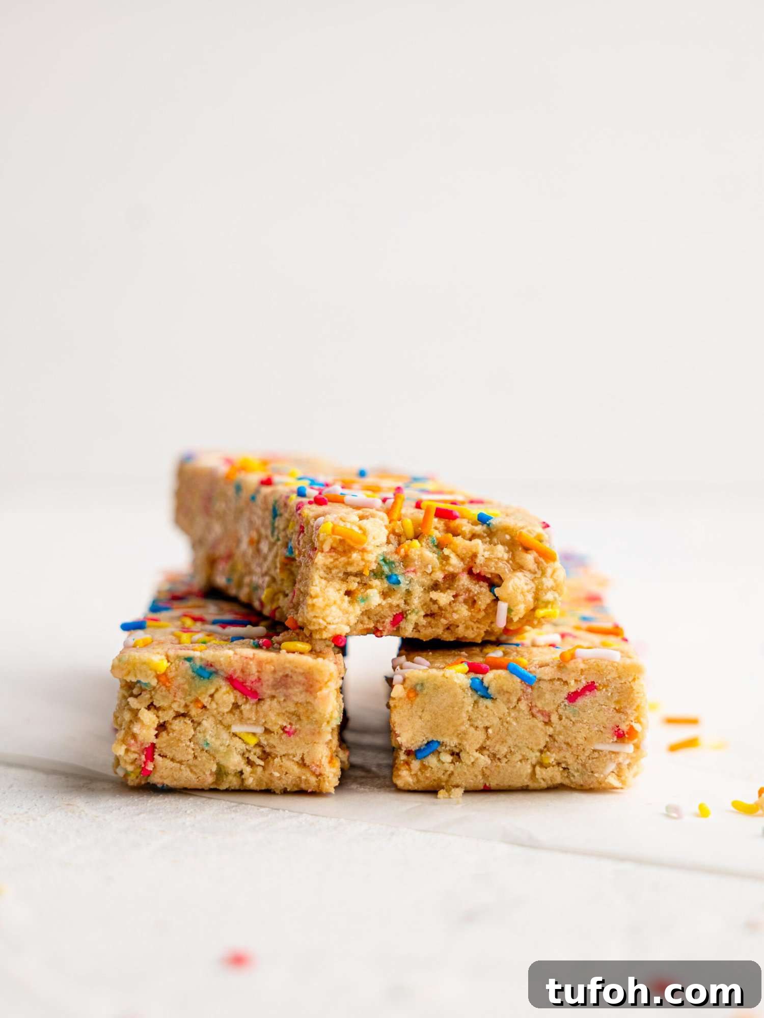Three birthday cake protein bars, a bite is missing from one.