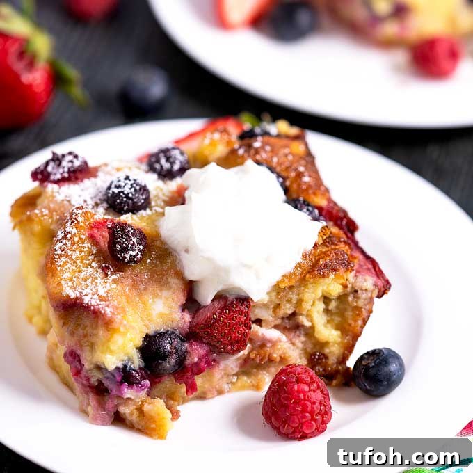 Tender and rich bread pudding topped with whip cream and garnished with fresh berries.