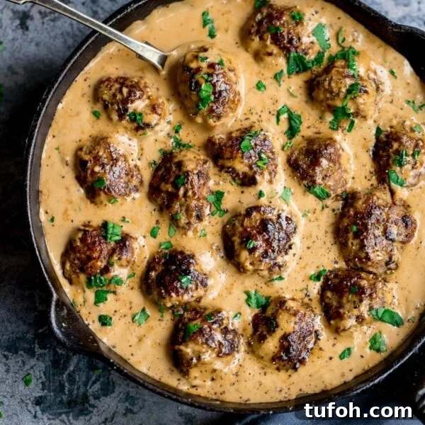 Swedish meatballs and gravy in a pan on a mottled blue background.