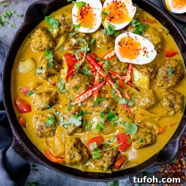 Meatballs with a Chinese Curry Sauce in a cast iron pan with boiled egg slices.