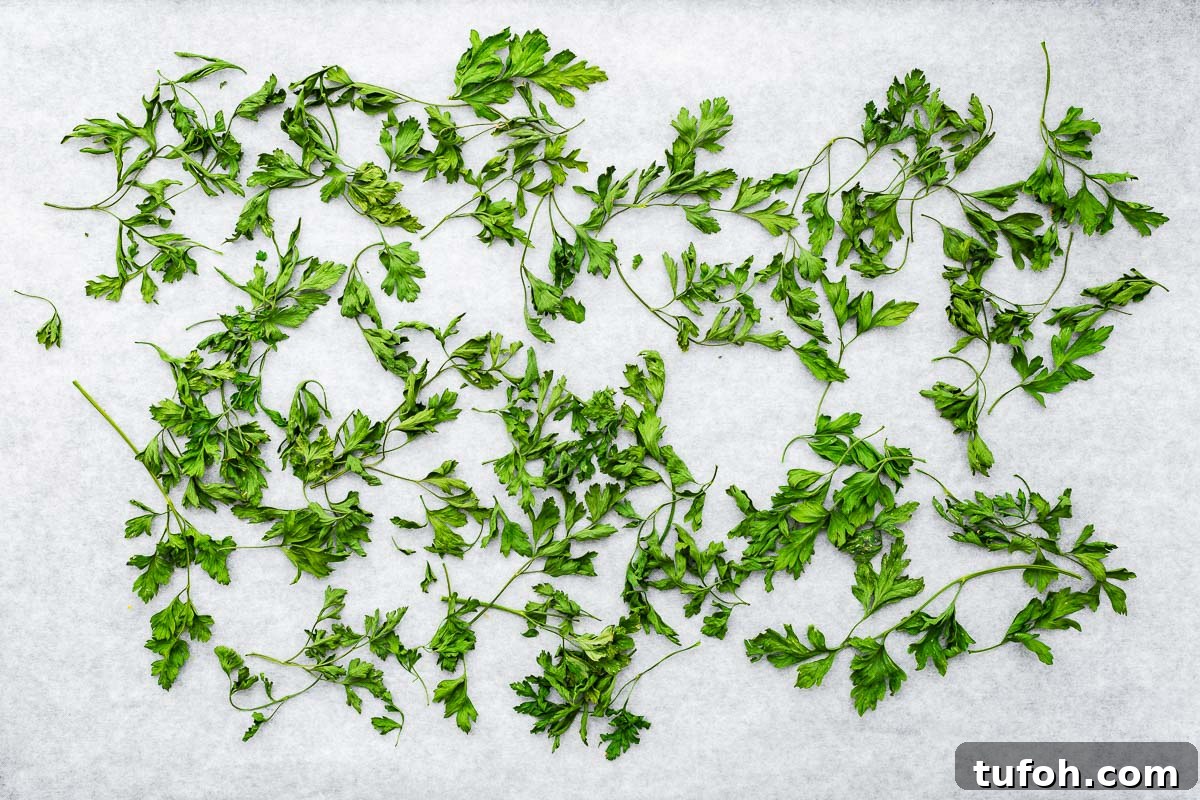 Oven-Dried Parsley: A Simple Guide for Long-Lasting Flavor 7 Oven dried parsley leaves and stems on parchment paper viewed from above.