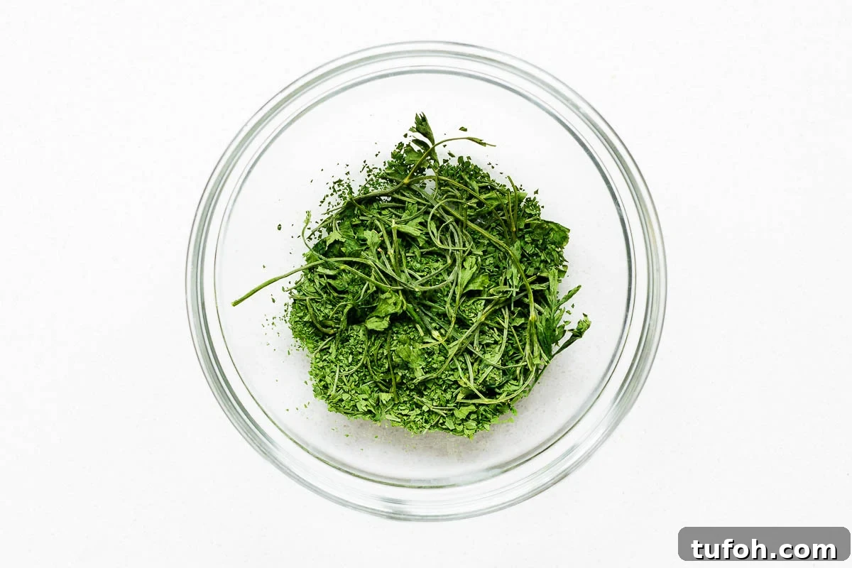 Oven-Dried Parsley: A Simple Guide for Long-Lasting Flavor 8 Roughly crumbled oven dried parsley with stems in a glass bowl.
