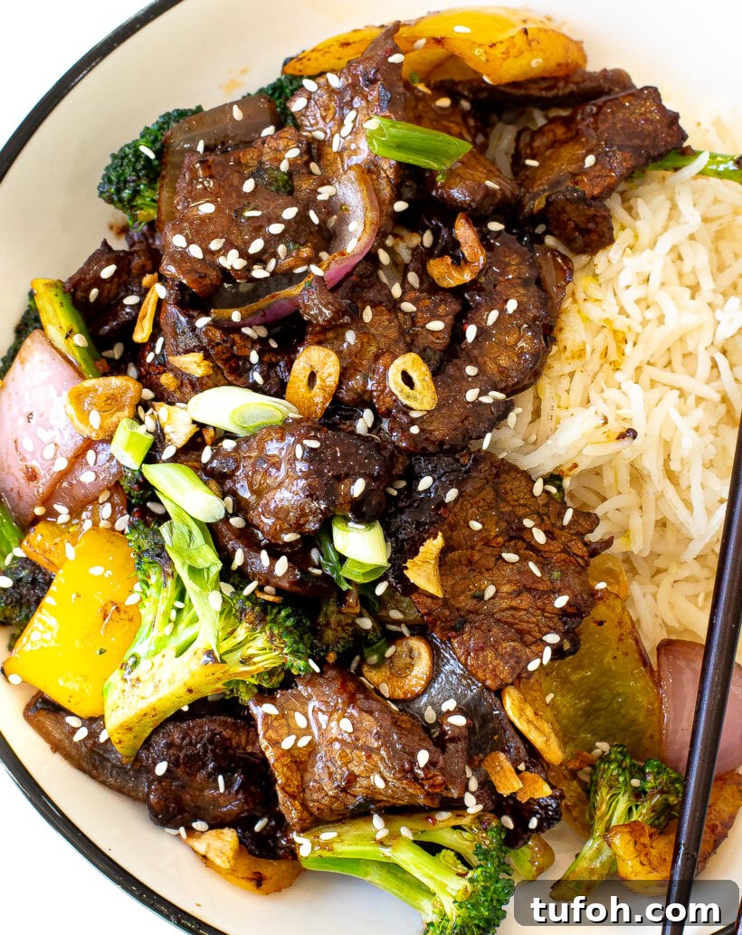 Close up view of beef stir fry in a bowl with rice.