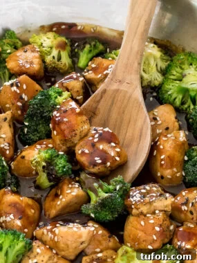 honey garlic chicken in a large skillet with a wooden spoon