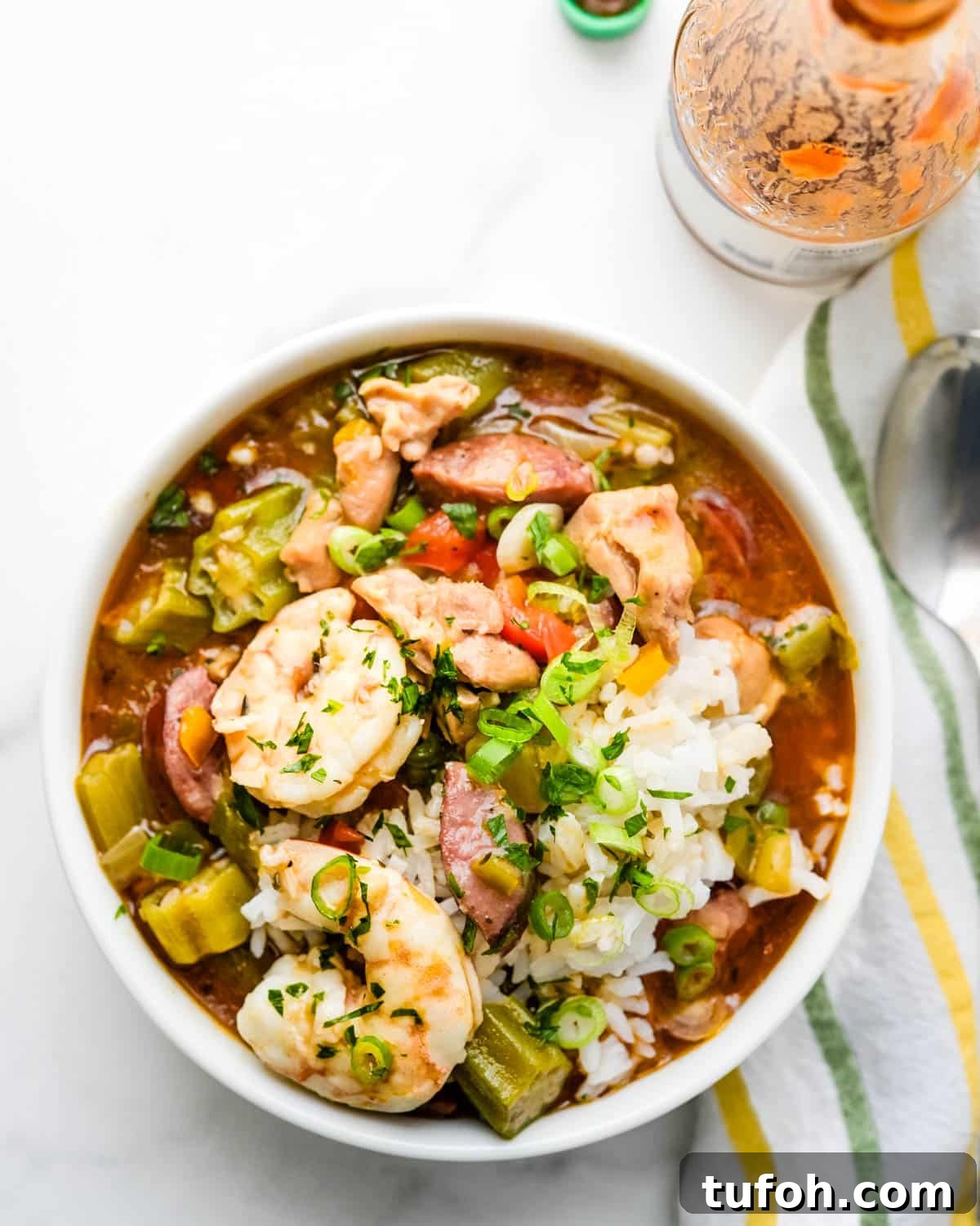 Enjoying a bowl of homemade gumbo with hot sauce.
