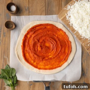 Fresh tomato pizza sauce spread on top of raw pizza dough.