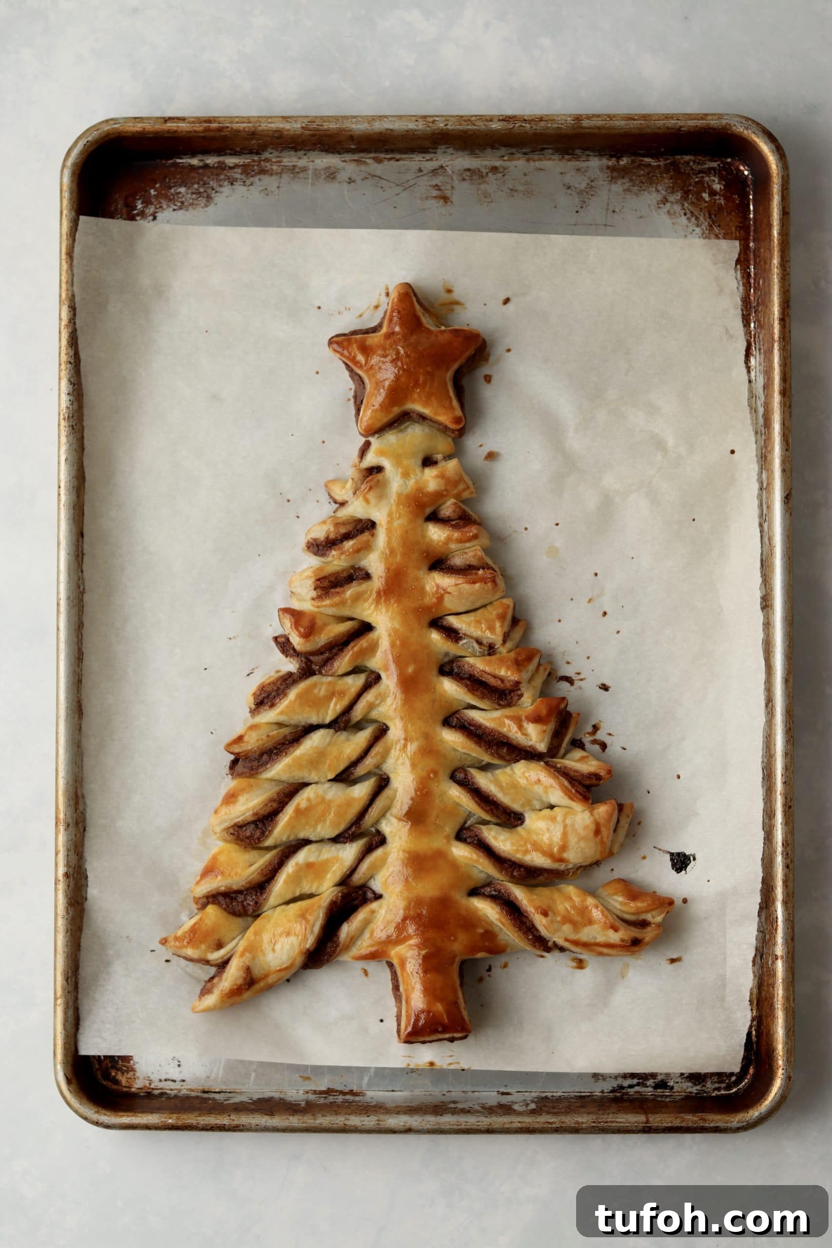 golden brown puff pastry Christmas tree on baking sheet.