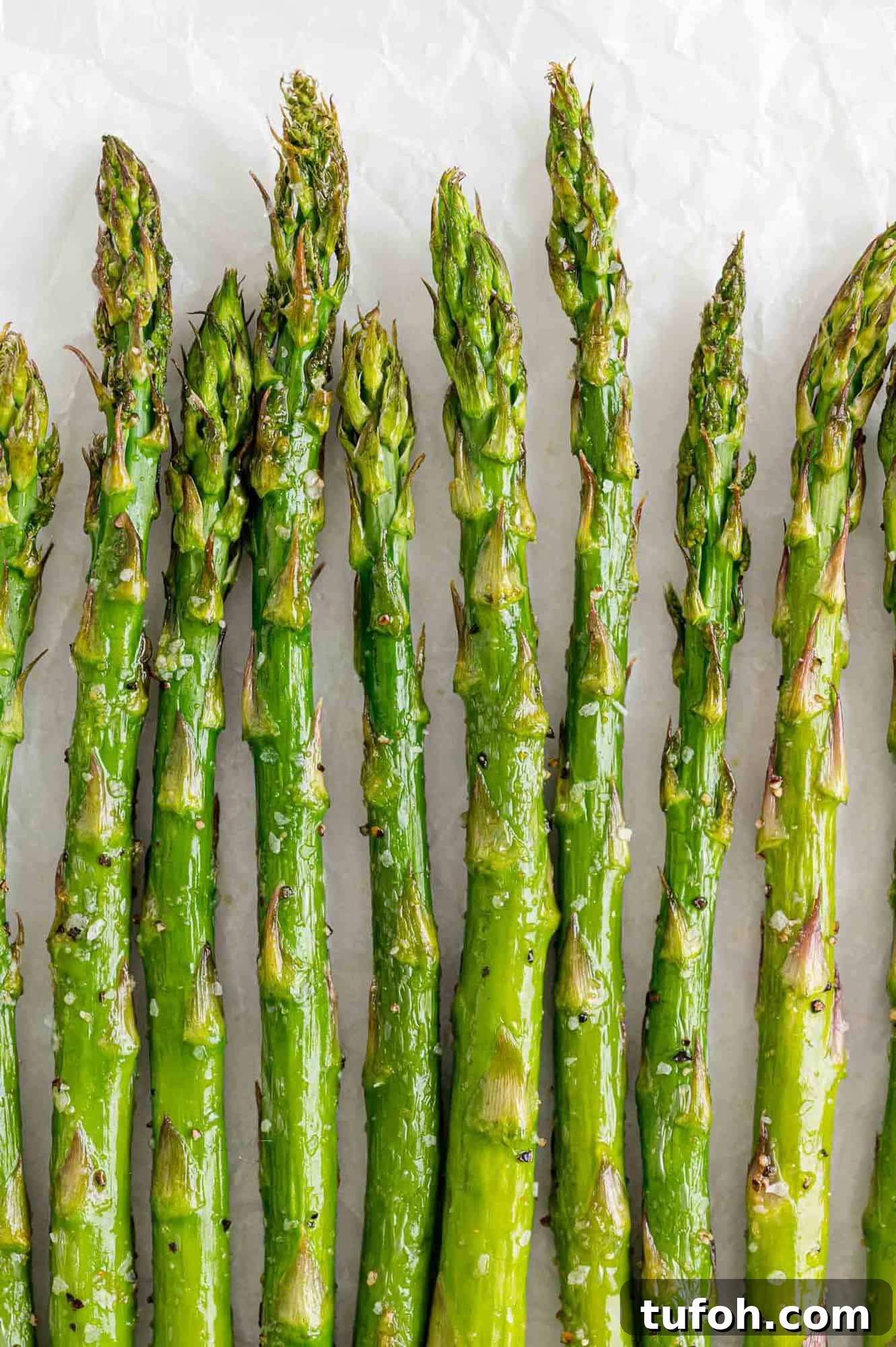 Crispy Air Fryer Asparagus in Minutes 2 Air fryer asparagus lined up in a single layer on a white background.
