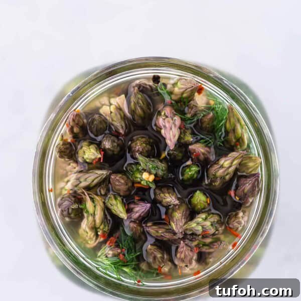 Crispy Air Fryer Asparagus in Minutes 11 Pickled asparagus in a jar, photographed from above, showing the flowery ends of the asparagus spears.