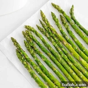Crispy Air Fryer Asparagus in Minutes 15 Air fryer asparagus laid flat on a white surface.