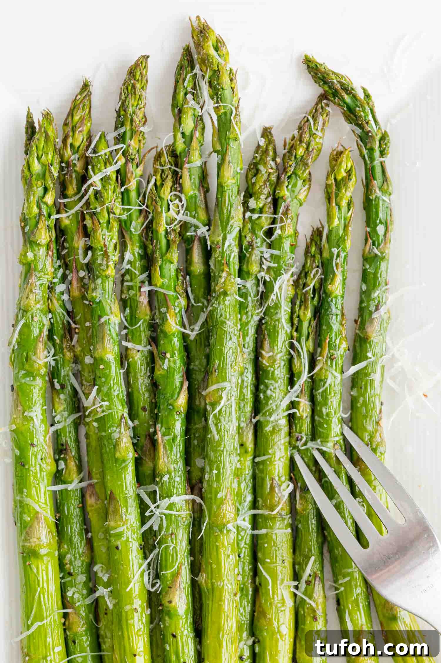 Crispy Air Fryer Asparagus in Minutes 3 Asparagus with cheese and a fork.