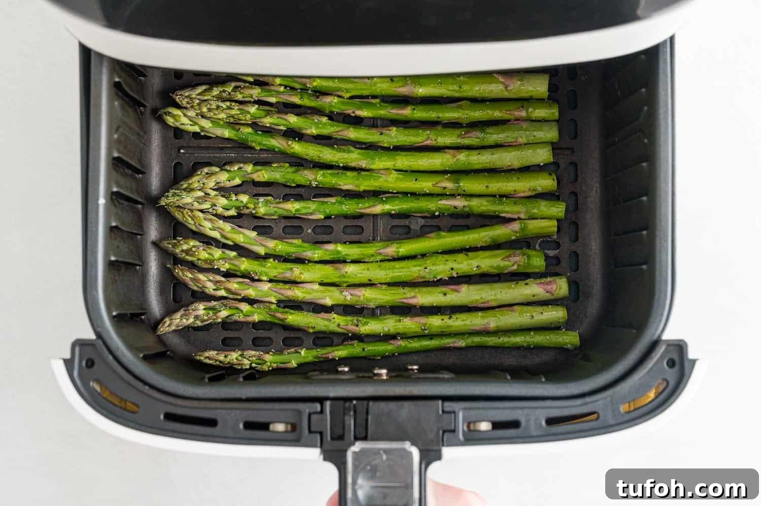 Crispy Air Fryer Asparagus in Minutes 8 Uncooked asparagus in an air fryer basket.