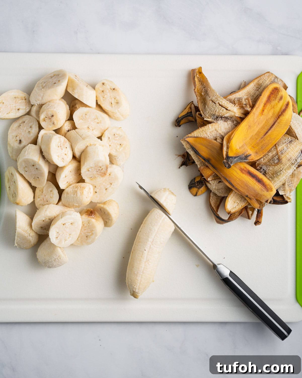 Knife cutting bananas into slices on a cutting board.