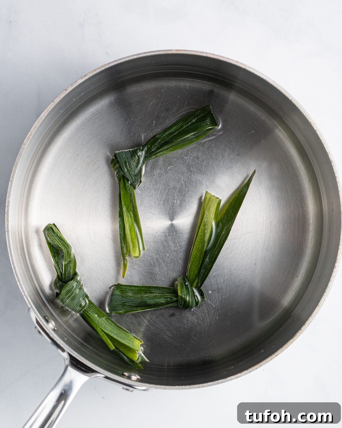 Three pandan leaves tied in a knot in a pot of water.