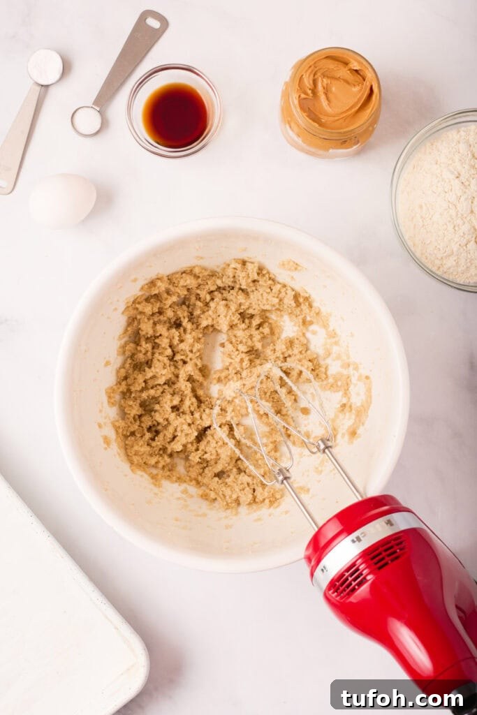 Chewy Peanut Butter Cookies Recipe with Crispy Edges 5 Creamed butter, shortening, and sugars mixed together in a white bowl with a red hand mixer resting nearby.
