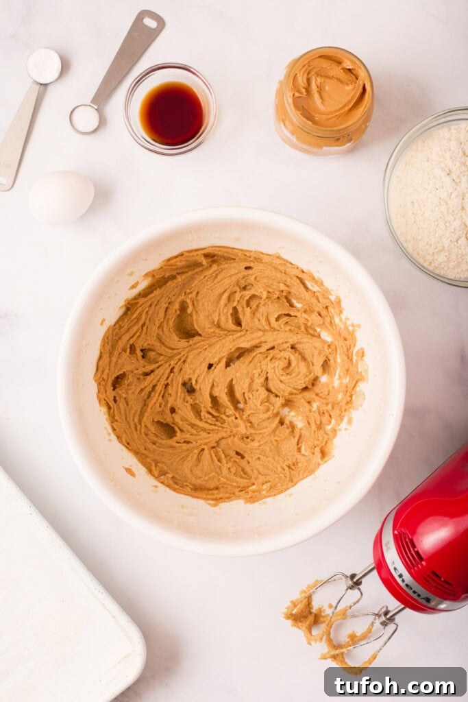 Chewy Peanut Butter Cookies Recipe with Crispy Edges 7 Peanut butter cookie dough after being mixed smooth and creamy in a white bowl using a red hand mixer.