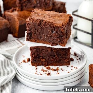 Thick and fudgy homemade sourdough brownies stacked on a white plate.