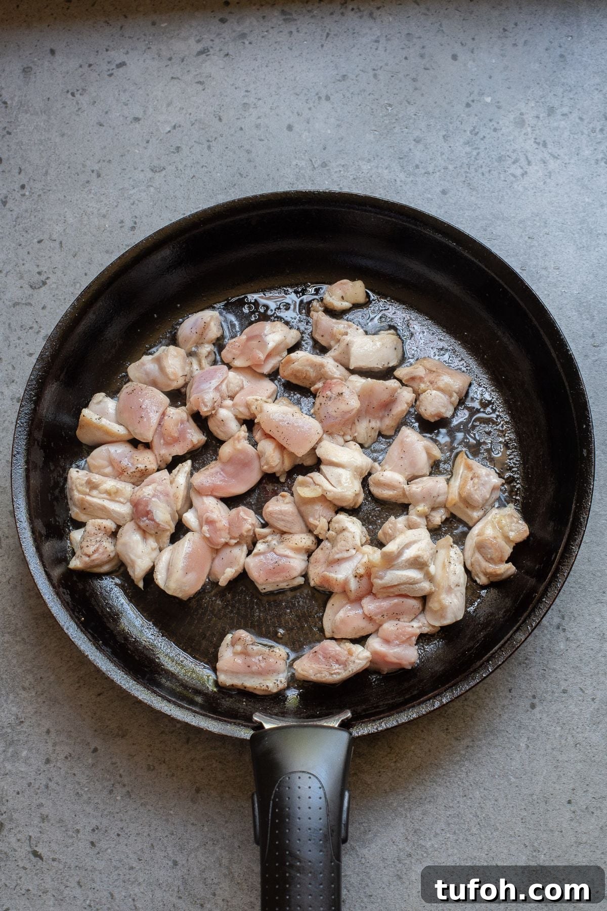 Raw seasoned chicken in skillet