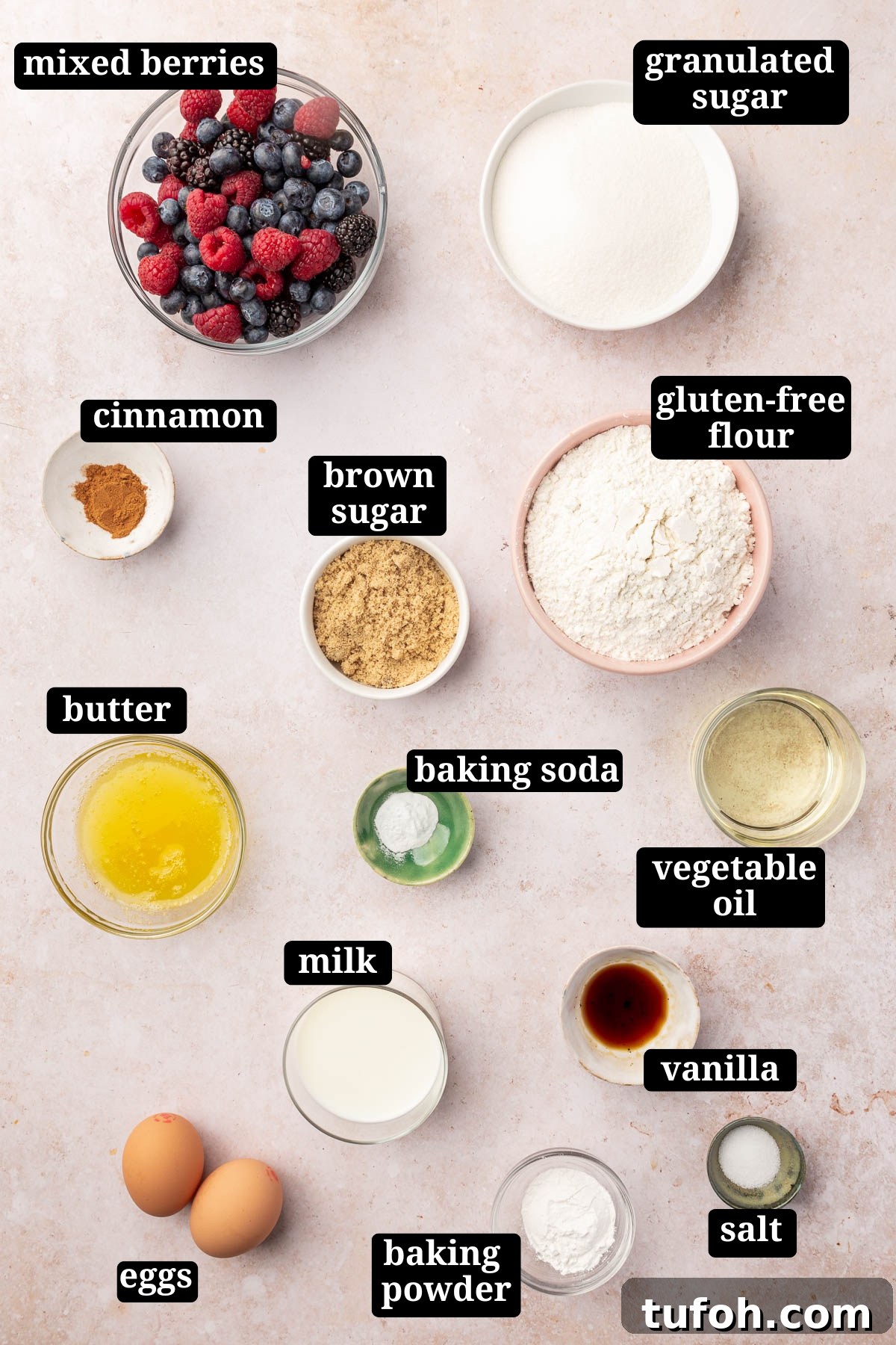 Gluten-Free Mixed Berry Muffins Recipe — Light, Moist & Berry-Packed 3 Ingredients in small bowls to make gluten-free mixed berry muffins with streusel, including mixed berries, granulated sugar, cinnamon, brown sugar, gluten-free flour, butter, baking soda, vegetable oil, milk, vanilla, salt, baking powder and eggs with text overlays over each ingredient.