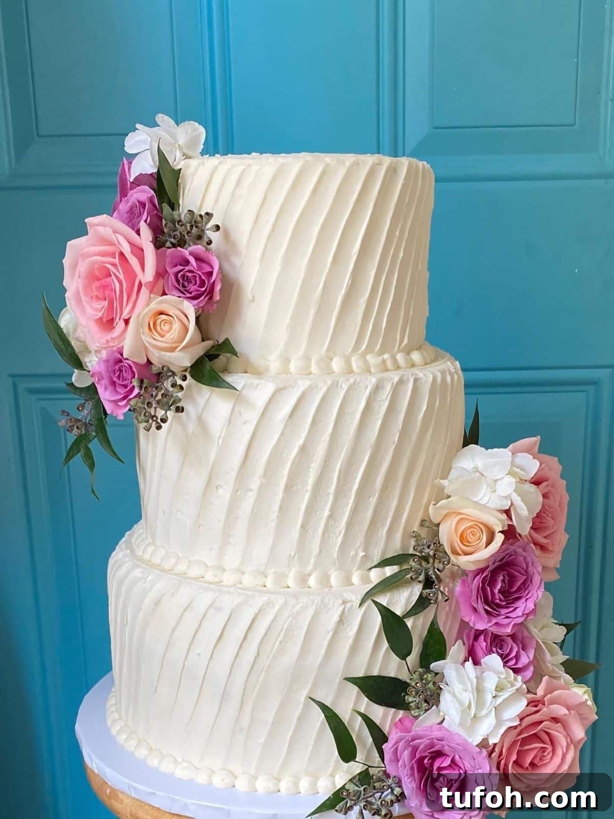 How to Safely Transport a Wedding Cake: 7 Proven Tips 2 A three-tiered wedding cake with white buttercream and fresh flowers.