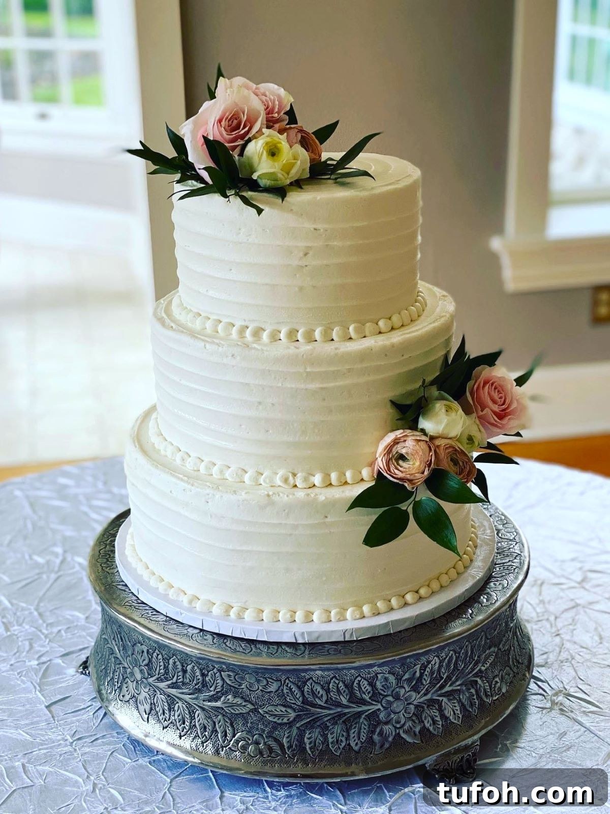 How to Safely Transport a Wedding Cake: 7 Proven Tips 7 A three-tiered wedding cake that has been transported on a cake drum and then placed on a cake stand at the event venue.