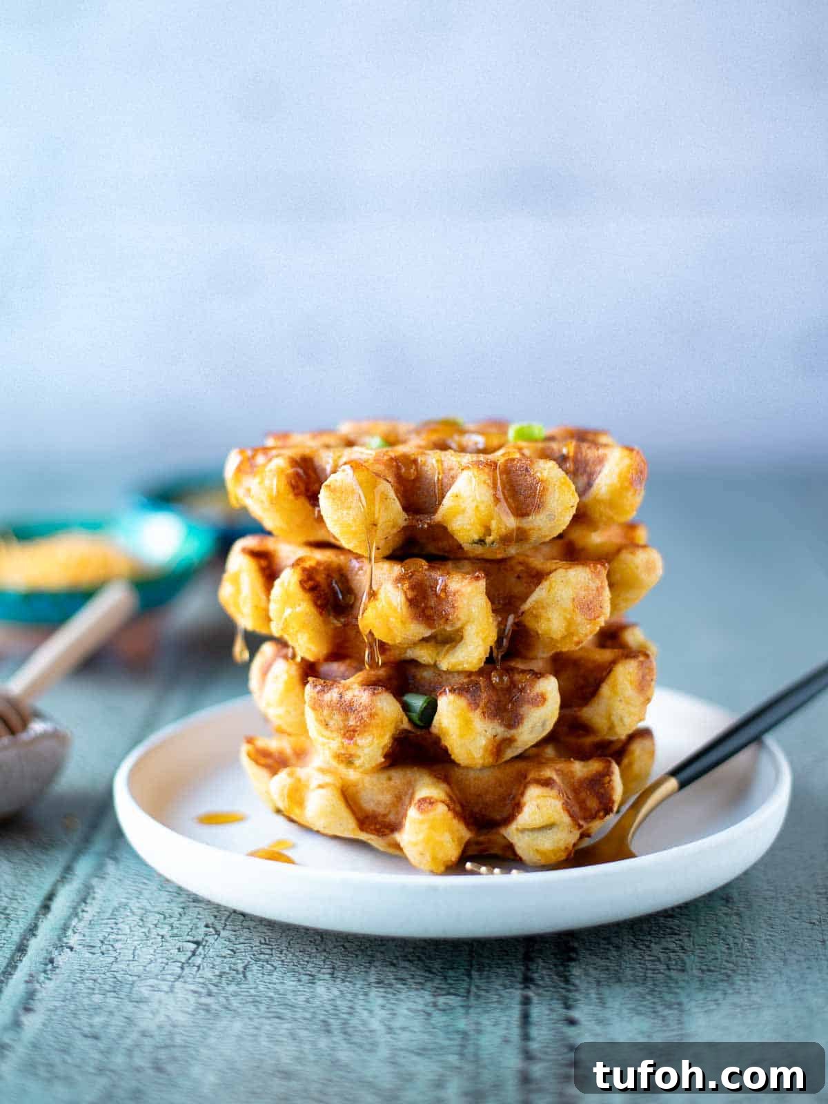 Spicy Green Chili Cheddar Waffles for Savory Brunch 2 Stack of savory waffles on a white plate with a fork to the right.