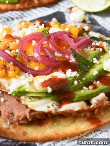 Huevos rancheros tostadas on newspaper with a lime in the background.