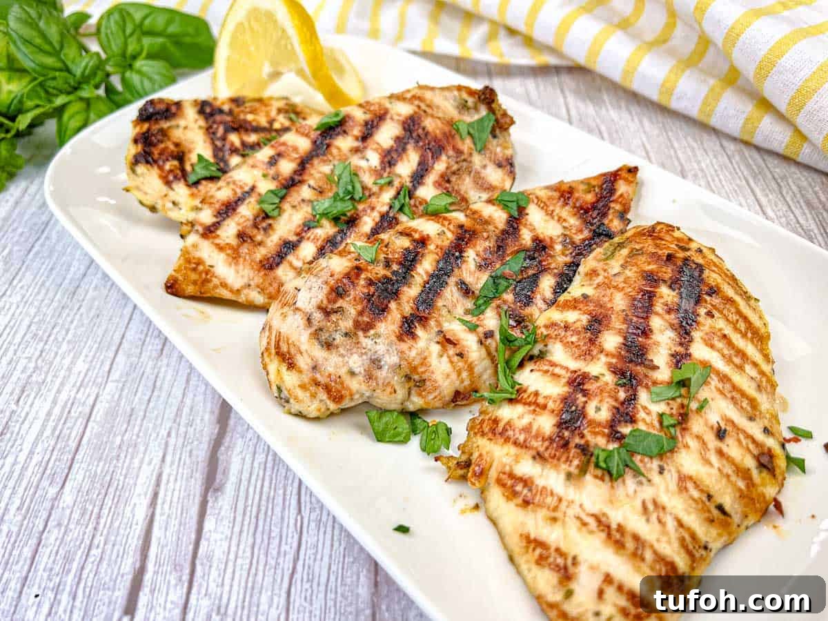 17 Crowd-Pleasing Backyard BBQ Recipes for Seconds-Worthy Meals 2 Four pieces of Ninja Woodfire Grill Lemon-Herb Chicken served on a white rectangular plate.