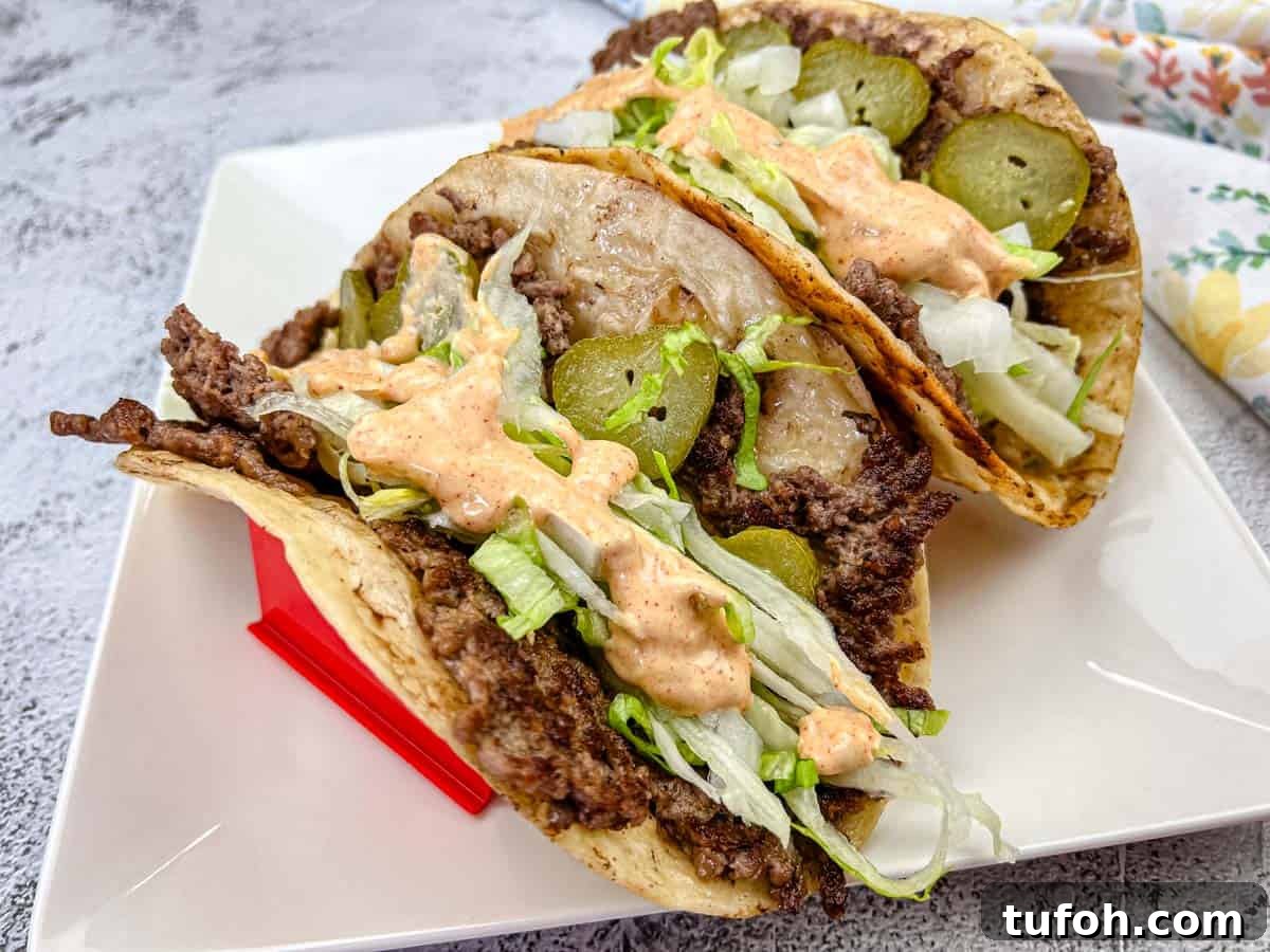 17 Crowd-Pleasing Backyard BBQ Recipes for Seconds-Worthy Meals 15 Two Big Mac tacos filled with ground beef, shredded lettuce, and pickles, and drizzled with a creamy sauce, placed on a white plate.