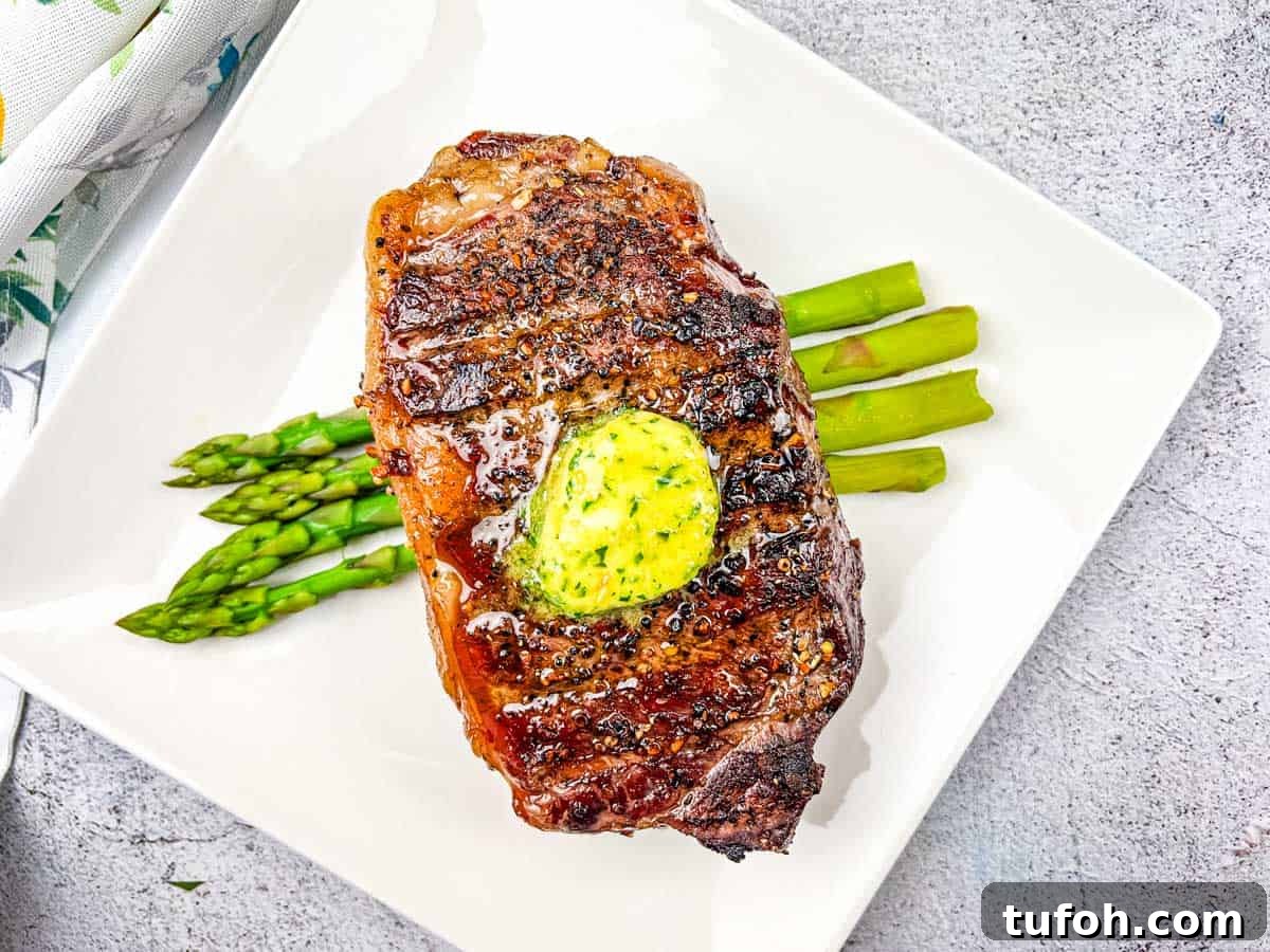 17 Crowd-Pleasing Backyard BBQ Recipes for Seconds-Worthy Meals 16 Reverse Seared Smoked Steaks with Smoked Garlic Butter on a plate with asparagus.