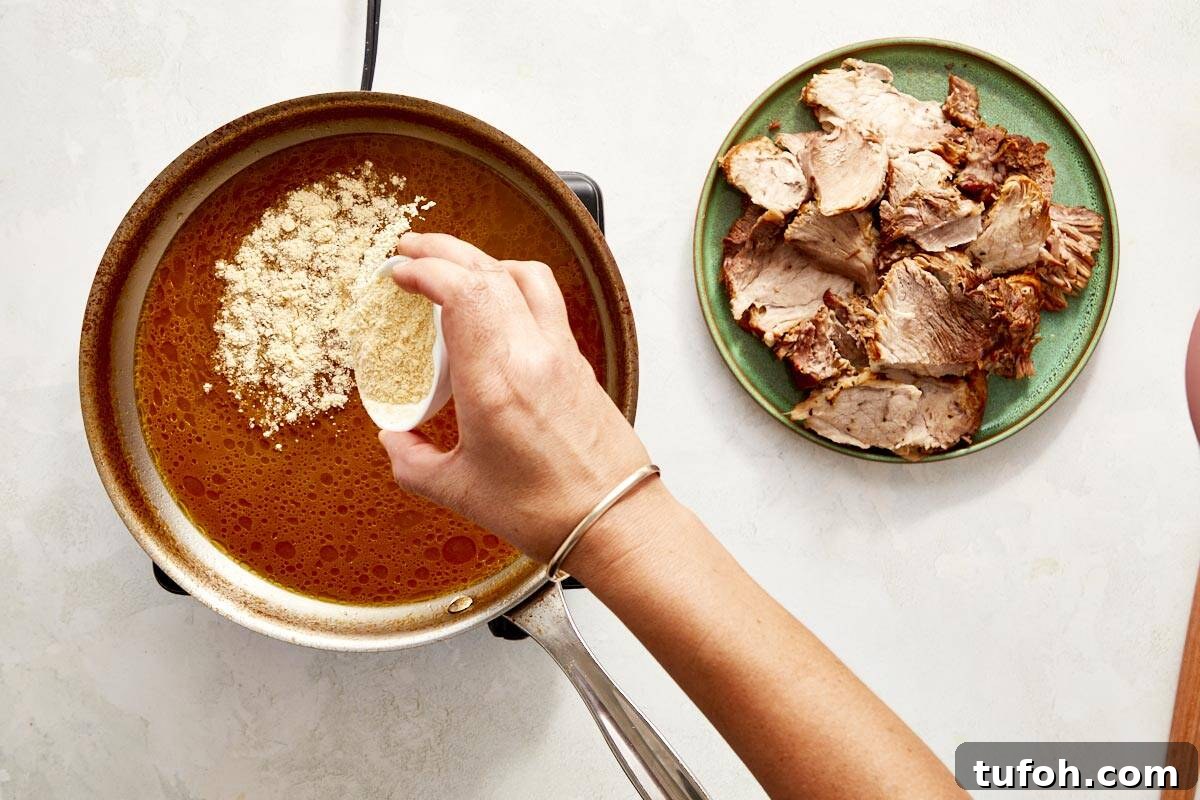 Hand adding cornflour to sauce in a pan