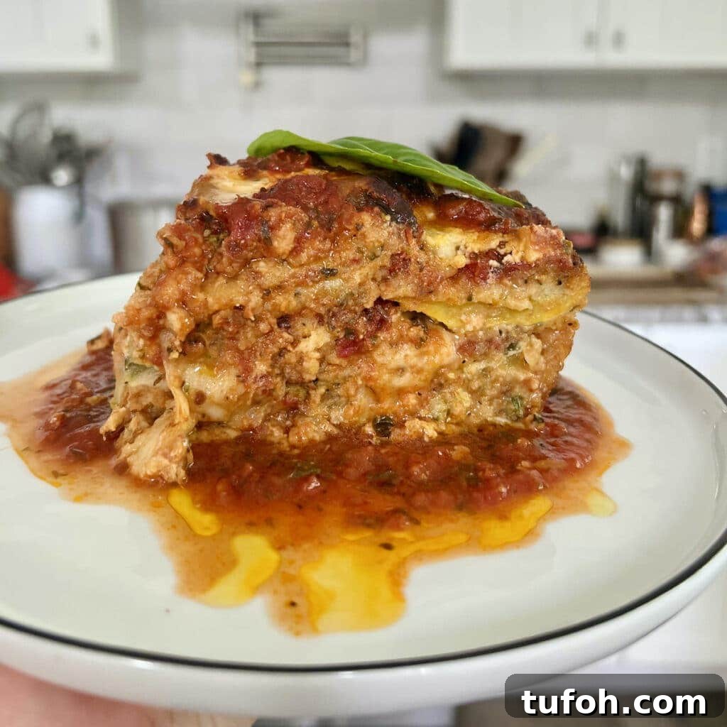 Zucchini Parmigiana with Ricotta: Layered Baked Zucchini Parmesan 2 Slice of zucchini parmigiana on white plate with stove and kitchen in background.