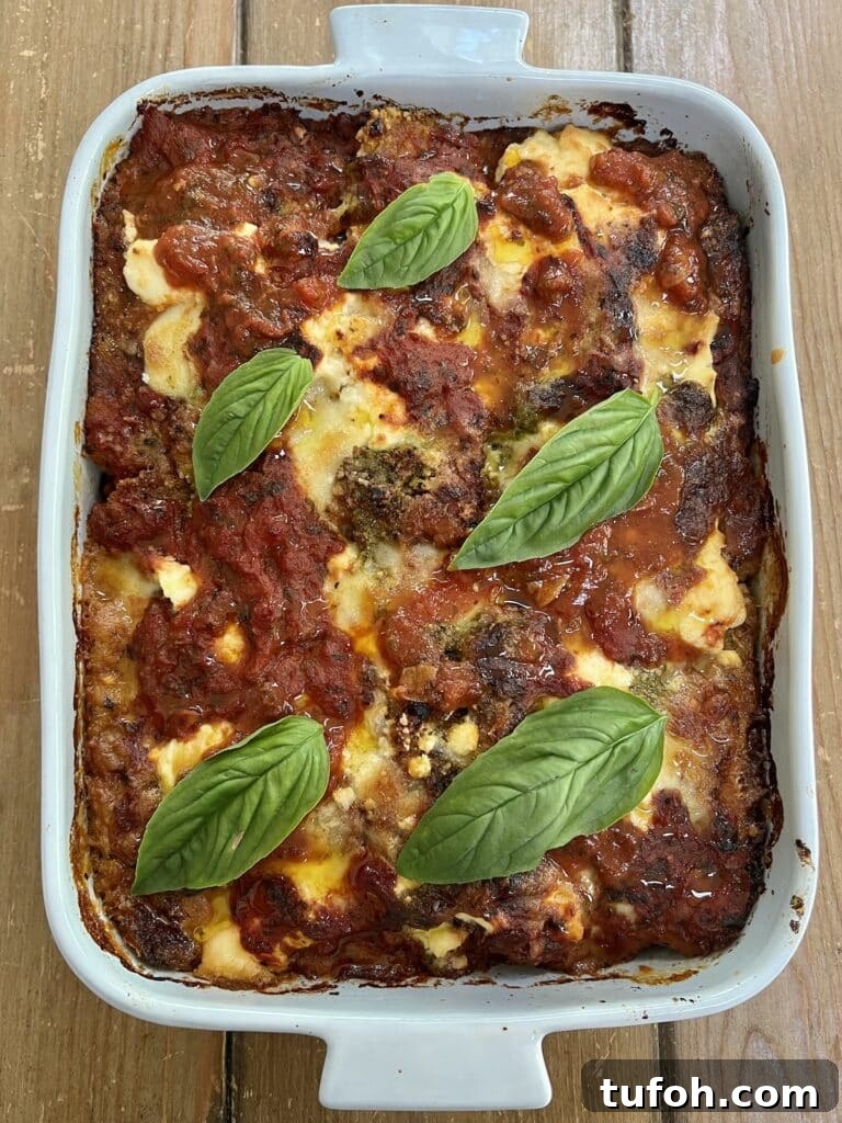Zucchini Parmigiana with Ricotta: Layered Baked Zucchini Parmesan 17 The finished baked zucchini parmigiana (parmesan) in baking dish with basil garnish.
