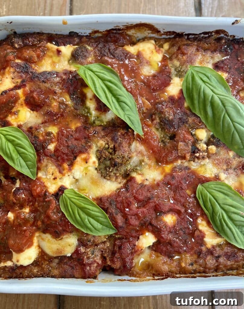 Zucchini Parmigiana with Ricotta: Layered Baked Zucchini Parmesan 18 The finished baked zucchini parmigiana (parmesan) in baking dish with basil garnish.