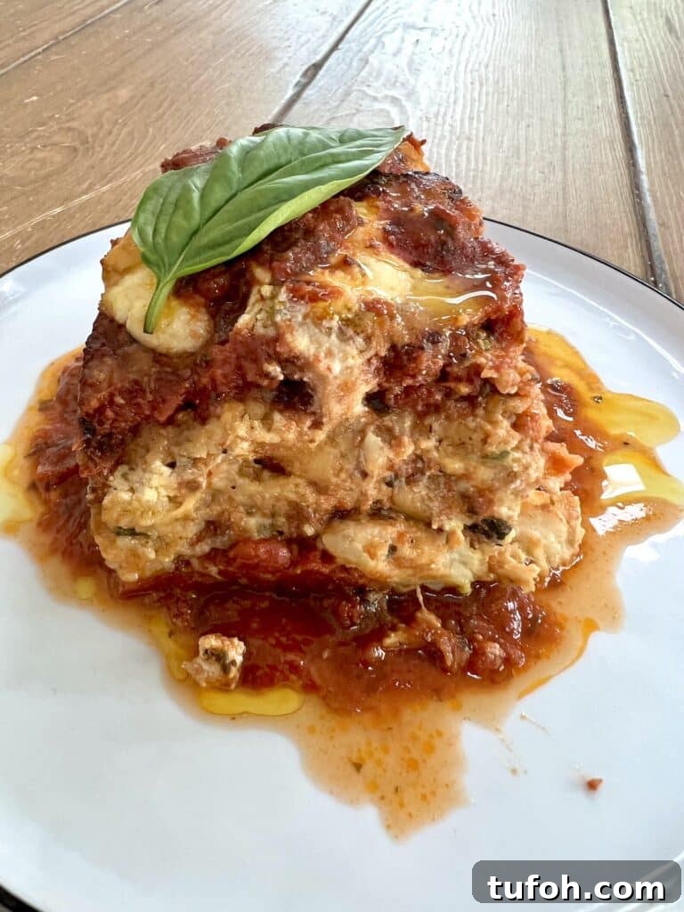 Zucchini Parmigiana with Ricotta: Layered Baked Zucchini Parmesan 20 Slice of zucchini parmesan (parmigiana) on white plate with extra sauce.